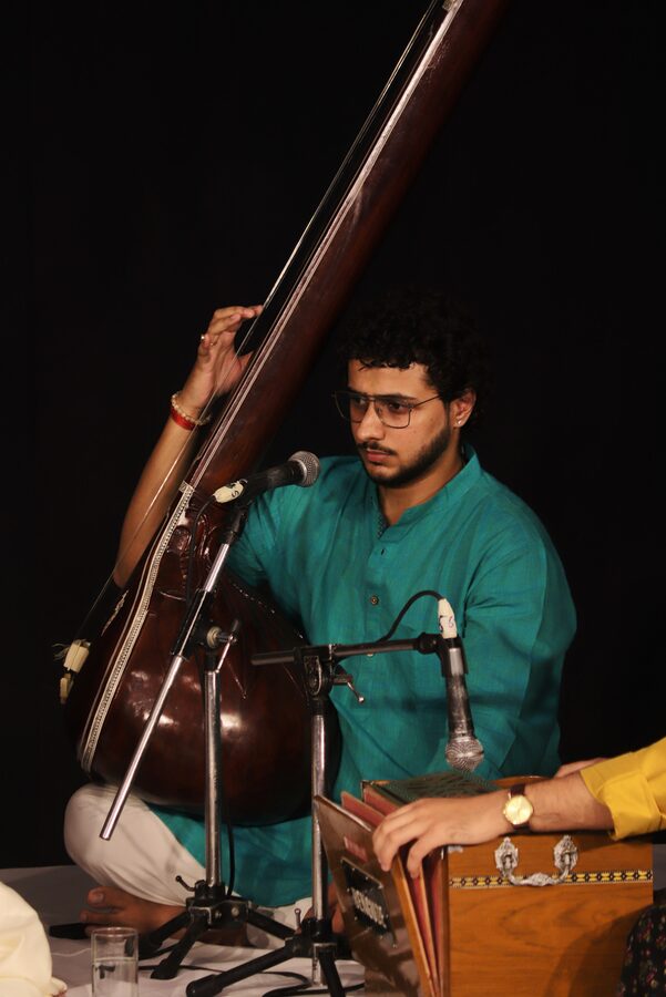 Ayush Sharma performing, holding a tanpura